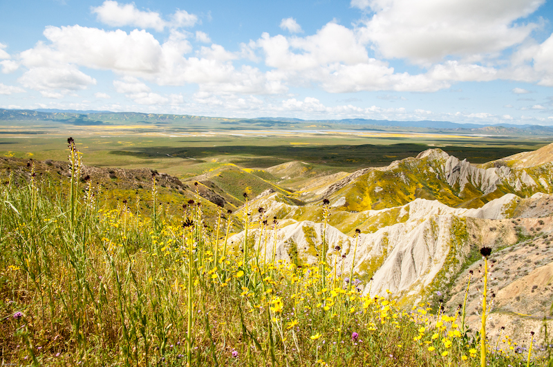 Expansive view of rugged landscape in the foreground with a large plain in the distance.